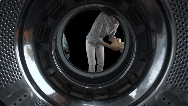 View from inside a washing machine of a housewife woman filling the drum with colored clothes. Green screen, isolated on black background with alpha channel.