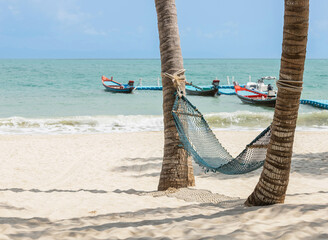 Hammock under coconut palm trees at sandy beach on sunny day, travel summer holidays concept