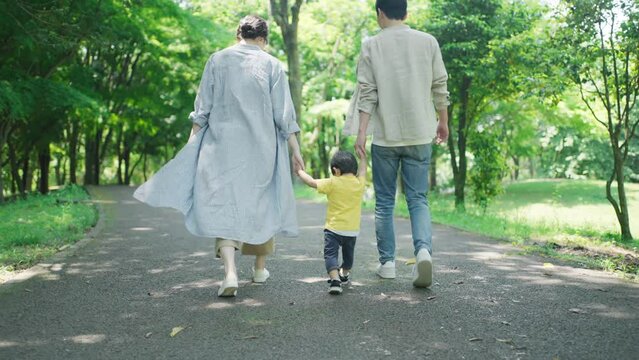 手を繋いで公園を歩く家族