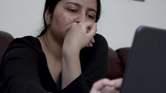 A teenage girl engages with her iPad while comfortably seated on the sofa, highlighting the integration of digital media into household settings for interactive multimedia and educational pursuits.