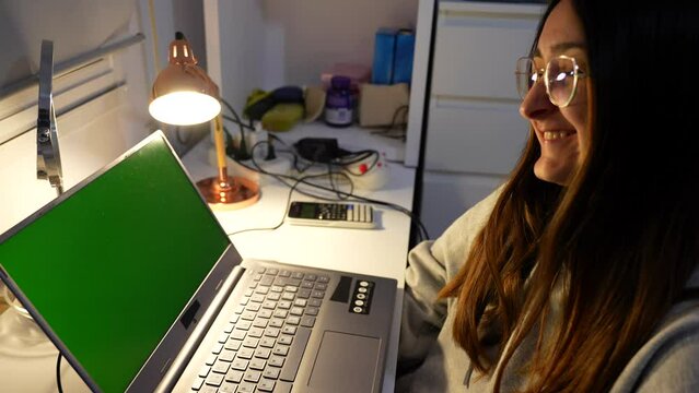 Green screen on laptop of cute woman laughing and waving at person on video call, ready to key