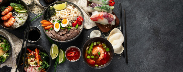 Traditional Asian food table. Spring roll, rice, shrimp, sushi, vegetables, meat on dark background