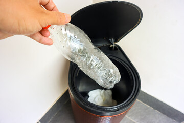 Environment care from home concept, close up of hand throwing an empty plastic bottle in a recycle bin