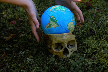 Fake human skull. Decorative skull. An artificial human skull and a small globe lie on the ground 
