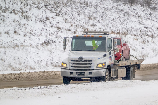 Calgary, Alberta, Canada. Mar 5, 2024. A towing company is pulling a car through the winter aftermath of a snowfall.