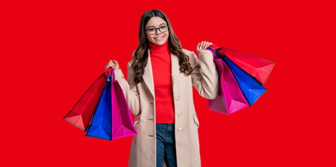 Girl shopping. Teen girl update wardrobe. Shopping sale and discount. Girl shopper with purchase isolated on red. Girl shopaholic hold shopping bag. Black Friday sale - obrazy, fototapety, plakaty