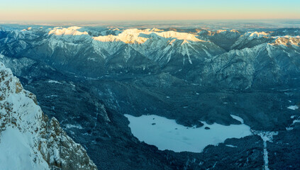 Fototapeta na wymiar View from Top of the Zugspitze which is Germanys highest mountain peak and down to the frozen lake Eibsee
