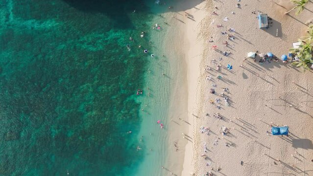 Top down view over beautiful Waikiki beach. Paradise island nature background. Copy space wallpaper of summer vacation on tropical Hawaii. People swimming in blue water and sunbathing in golden sun 4K