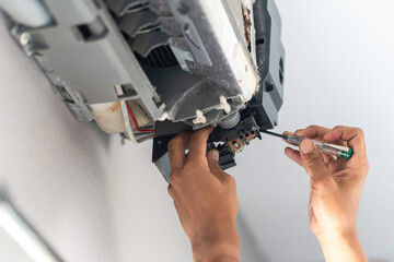Technician man using screwdriver to check and fix air conditioning system, Repairman service for...