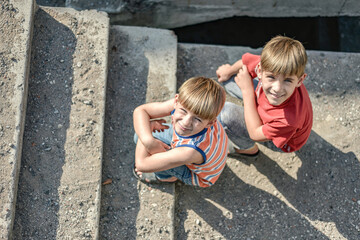 Two children are sitting on the steps of an abandoned building, a concept of the life of street...