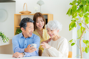 リビングでスマホを見るシニア夫婦と子供