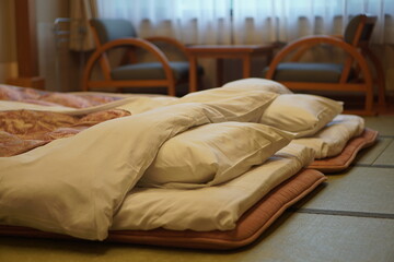 Inside the Japanese style bedroom with two futon mattresses on tatami mat. Luxury Ryokan in Japan.