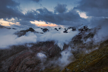 Abenddämmerung über dem Ramolhaus mit Blick auf den wolkenverhangenen Alpenhauptkamm mit...