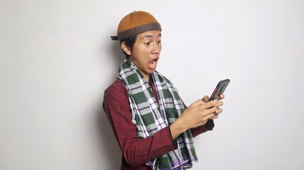 shocked Asian Muslim man playing, typing on smartphone