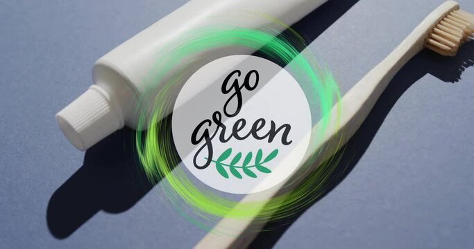 Animation of go green text and green ring over toothpaste tube and wooden toothbrush