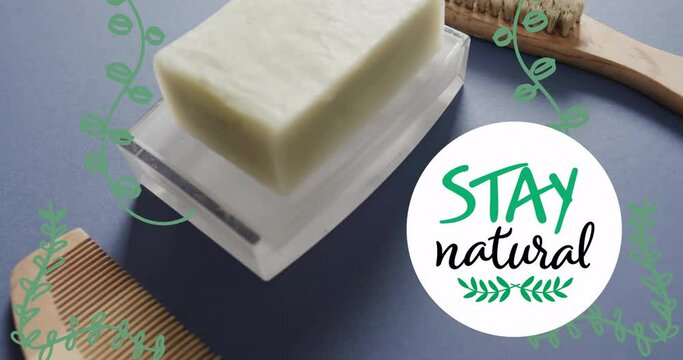 Animation of stay natural text and leaves over organic soap, wooden comb and brush