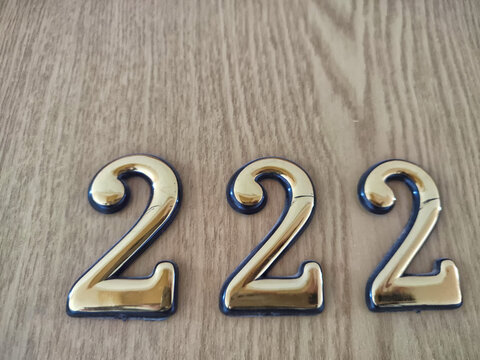 Three-dimensional brass numbers affixed to wood. Brass Numerals 222 Mounted on Wooden Surface