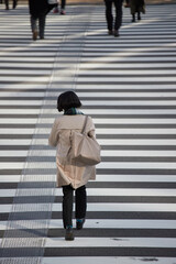 冬の朝の都市の交差点の横断歩道を渡る女性会社員の姿