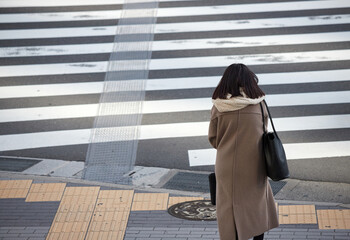 冬の都市の交差点の横断歩道で信号待ちの若い女性の姿