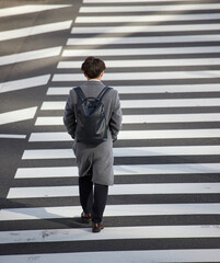 冬の朝の通勤時間の都市の交差点の横断歩道を渡るサラリーマンの姿