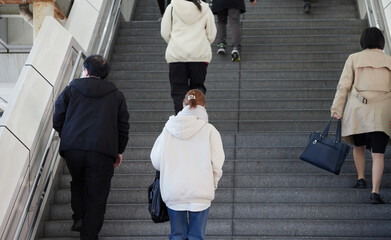 冬の朝の通勤時間の駅の階段を登る人々の姿