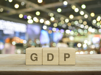 GDP letter on wood block cubes on wooden table over blur light and shadow of shopping mall, Gross...