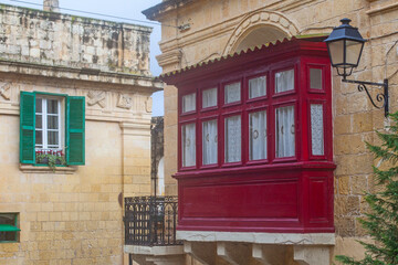 Red balcone on the Narrow street of ancient city Rabat with traditional maltese houses built of...