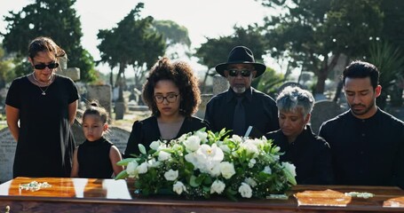 Family, sad and coffin at graveyard for funeral, service and burial ceremony with flower bouquet. Death, grief and people at cemetery with casket for loss, mourning and depression at memorial