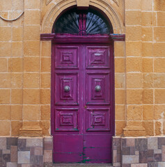 Violet doors on the Narrow street of ancient city Rabat with traditional maltese houses built of limestone, Victoria, Malta