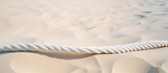 Fototapeta na wymiar Sunny Summer Day: Lone Rope Resting on the Tranquil Sandy Beach Shoreline