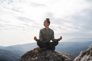 Abwaschbare Fototapete Yoga outdoors. Woman sits in lotus position zen gesturing. Concept of healthy lifestyle and relaxation. Meditation in the mountains © Соня Монштейн
