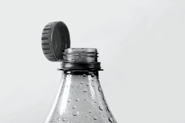 Close up of new cap attached to plastic bottle, isolated on gray background. Environmental protection concept.