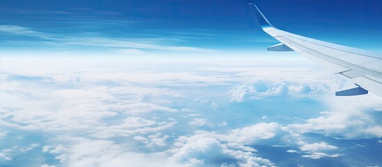 Aerial View of Airplane Wing Soaring Above Fluffy Clouds in Clear Blue Sky