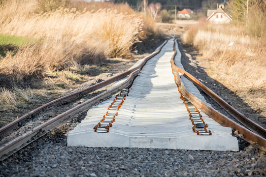 elements of a freshly laid railway line, loosely placed on the ground, steel rails, metal sleepers, ready for precise assembly