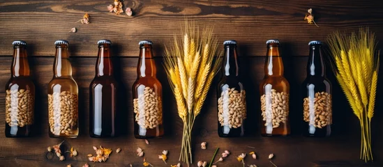 Zelfklevend Fotobehang Rustic Harvest: A Variety of Wheat Stalks and Bottles of Beer Arranged on a Wooden Table © Ilgun