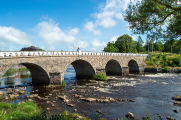 Fototapeta na wymiar Stone bridge over river, blue sky with some clouds