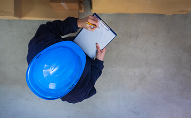 Top down view to warehouse worker in helmet checking box with pen and paper. Stock of Parcels with Products, transportation concept
