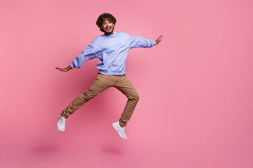 Photo of positive optimistic man wear stylish clothes fly air rejoice enjoy travel empty space isolated on pink color background