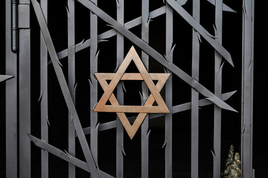 A jewish Star of David, made of golden metal on a black metal fence Dachau