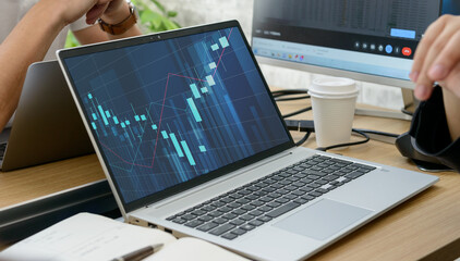 ノートパソコンで株価チャートを分析する男性