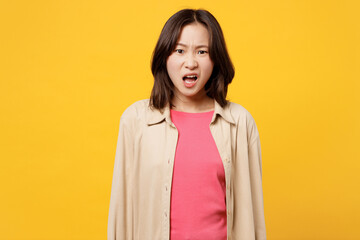 Young shocked scared sad woman of Asian ethnicity she wears pink t-shirt beige shirt pastel casual clothes look camera with opened mouth isolated on plain yellow background studio. Lifestyle portrait. - obrazy, fototapety, plakaty
