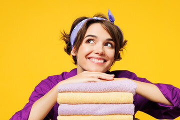 Close up young pensive happy woman wear purple shirt do housework tidy up put hand on pile of...