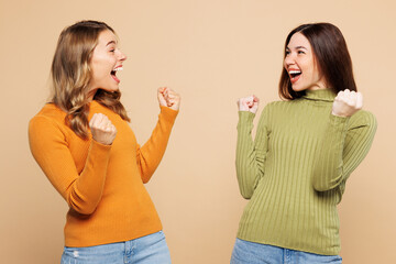Side view young friends two women they wear orange green shirt casual clothes together doing winner...