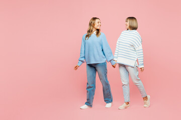 Full body happy cheerful elder parent mom with young adult daughter two women together wear blue casual clothes walk go look to each other isolated on plain pastel pink background. Family day concept.