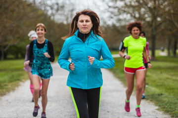 group of women running together through a tree-lined park