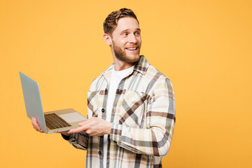 Side view young happy Caucasian IT man he wear brown shirt casual clothes hold use work on laptop...