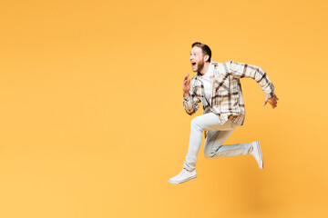 Fototapeta na wymiar Full body side profile view young Caucasian overjoyed man he wear brown shirt casual clothes jump high run fast hurry up isolated on plain yellow orange background studio portrait. Lifestyle concept.
