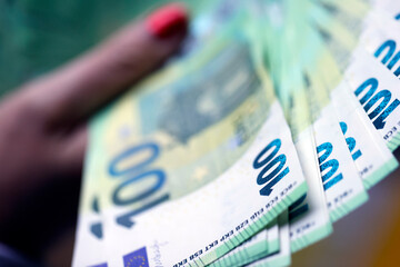 Business, finance, saving, banking and people concept. Close up of woman hands counting 100 euros...