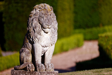 Sitting lion stone  statue in a park.