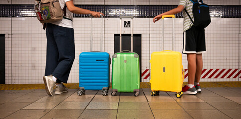 Travelers with colorful luggage waiting in a subway station.